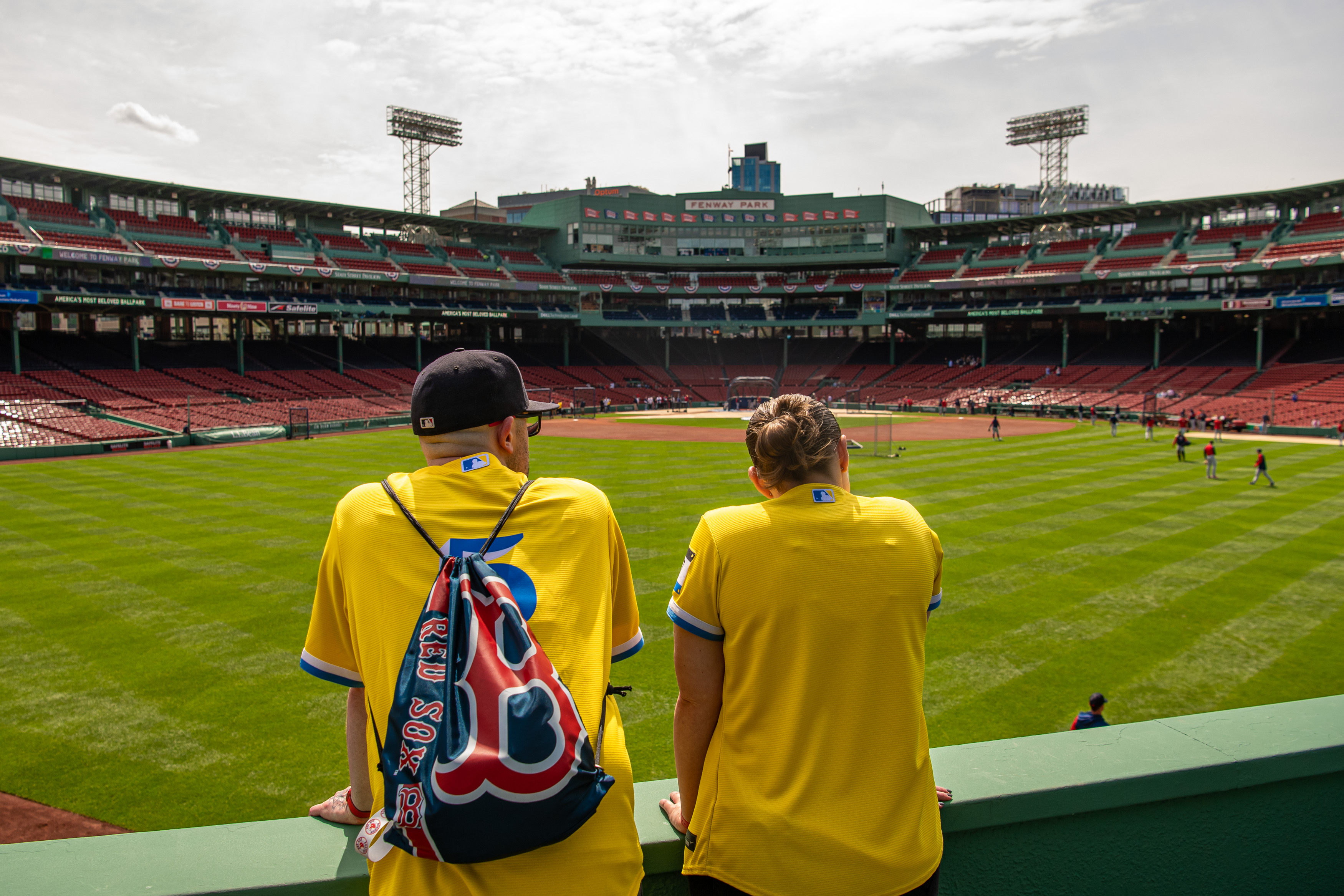 Two Red Sox fans looking at Fenway Park from center field stands.